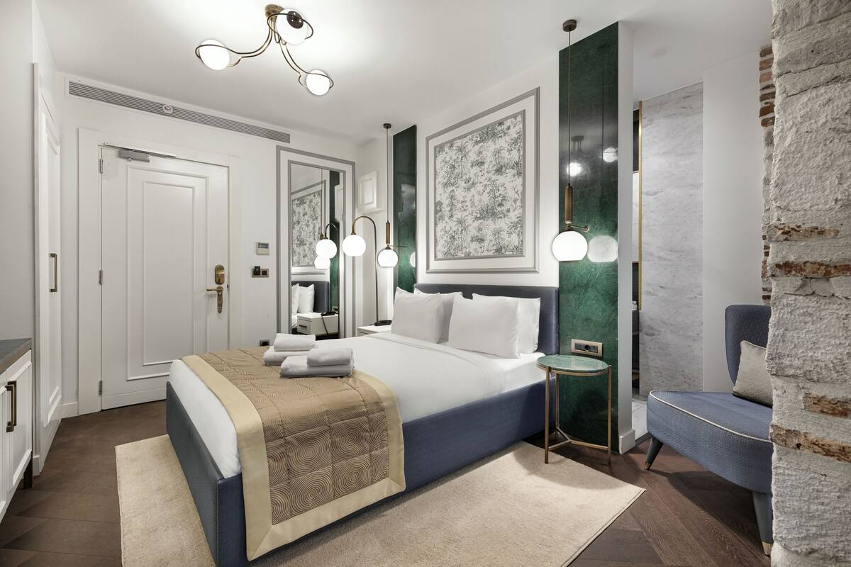 Une chambre moderne avec un grand lit, des tables de chevet, un miroir et une vue sur un mur en briques.