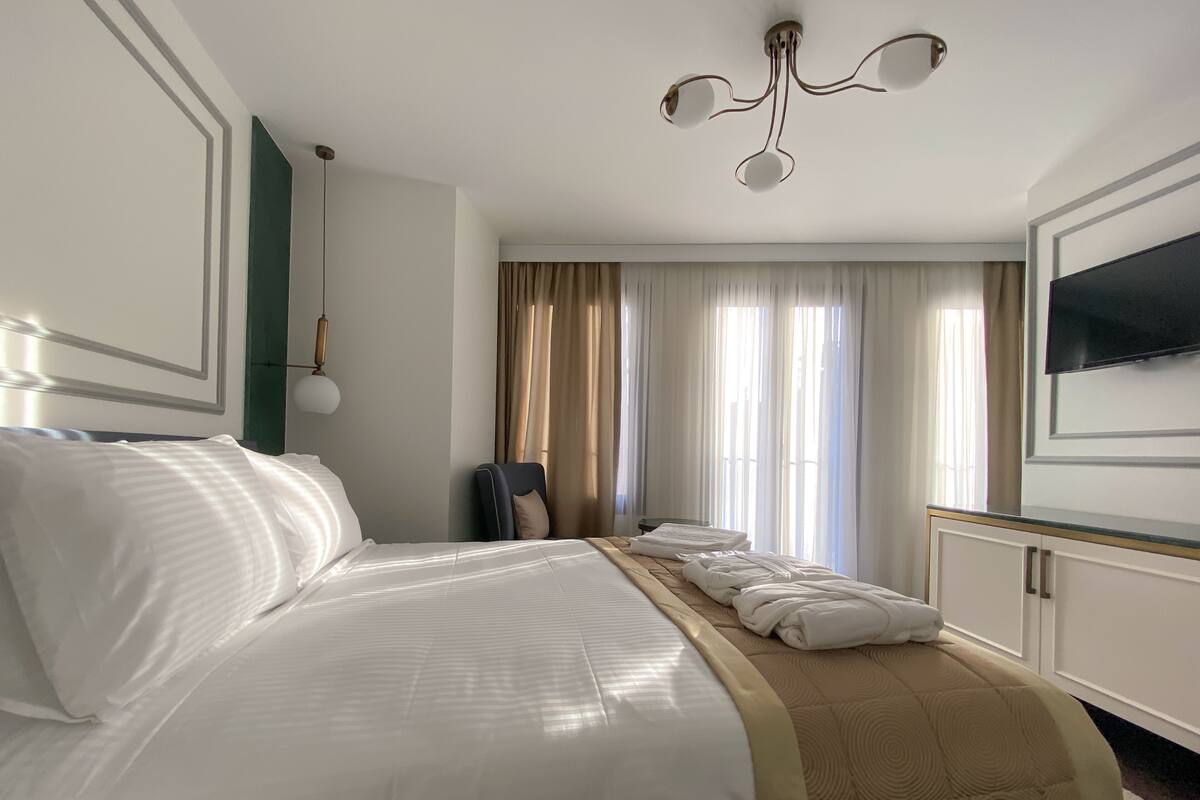 Une chambre d’hôtel avec un grand lit, un bureau, une chaise et un téléviseur fixé au mur.