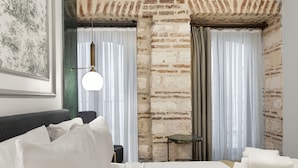 A hotel room with a brick wall, a bed with white linens, a small table, and a hanging light fixture. - Pera Rasso Hotel Boutique Hotel (Istanbul)