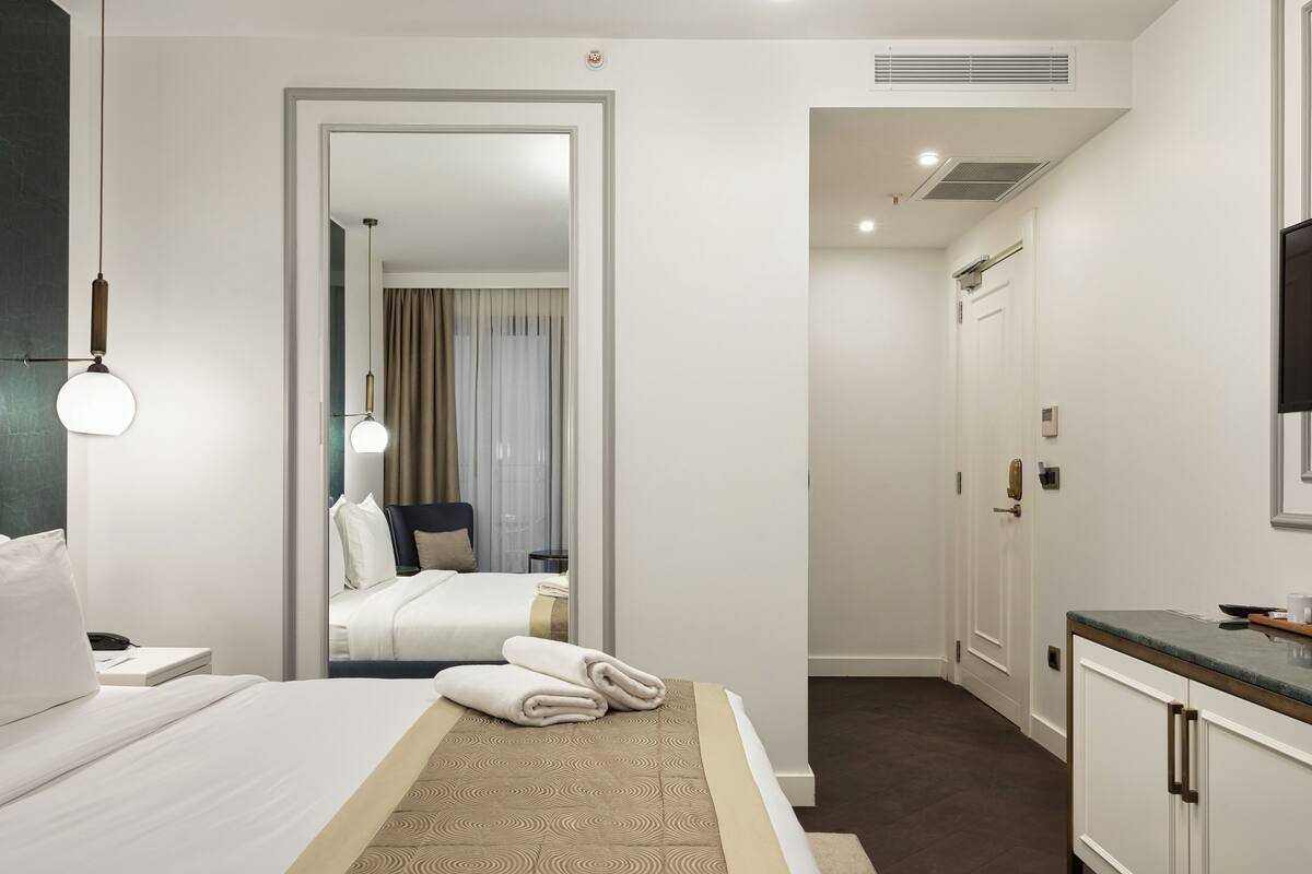 Une chambre d’hôtel comprenant un lit, un bureau, une chaise, un miroir, une télévision et une salle de bain.