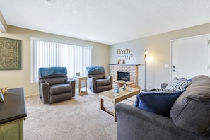 Relax in a cozy seating area with a sofa, recliner chairs, and a fireplace.