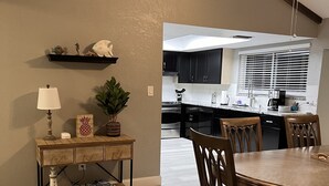 Un coin repas avec une table et des chaises en bois, une lampe et une plante posée sur une console.