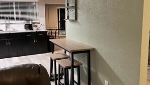 Une cuisine moderne avec un coin repas, un canapé en cuir marron et une table en bois avec des tabourets.