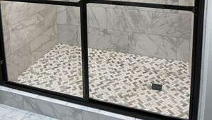 A walk-in shower with a glass door, marble tiles, and a patterned floor. - Riverside Condo w/ Deck (Pigeon Forge)
