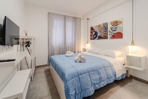 Une chambre d’hôtel moderne dotée d’un grand lit, d’une télévision à écran plat, d’un bureau et d’œuvres d’art accrochées au mur.
