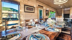 Un espace repas avec des murs en bois, des tableaux encadrés et une vue dégagée grâce à de grandes fenêtres.