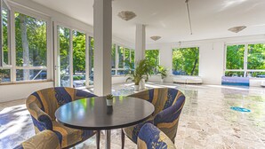 A spacious indoor area with large windows, a round table, and patterned chairs.