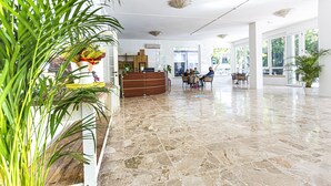 A spacious lobby with a marble floor, a reception desk, and several seating areas.