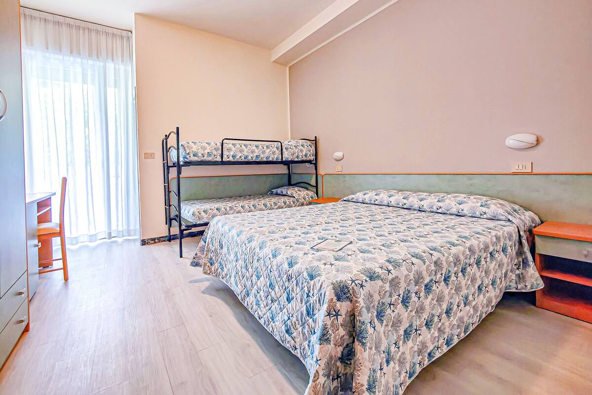Een kamer met stapelbedden, een bureau en een stoel.