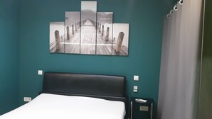 Une pièce comprenant un lit, une œuvre d’art fixée au mur représentant un pont et un rideau.