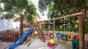 A playground with a blue slide, swings, and tire swings. - Holiday apartment with pool and air conditioning (Poreč)