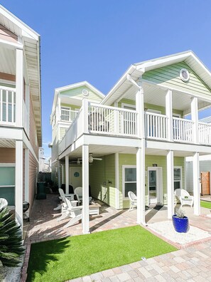 A residential building with a covered porch, outdoor seating, and a well-maintained lawn. - Laguna Beach PCB 5/3, STEPS TO THE BEACH-5 STAR RENTAL- CONVENIENT TO EVERYTHING (PANAMA CITY BEACH)