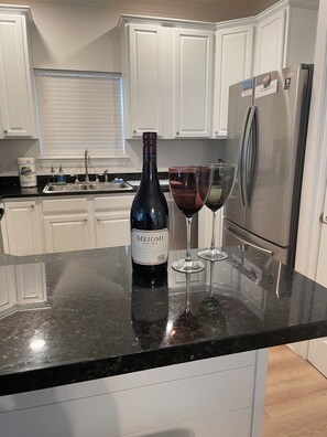 Une cuisine avec un réfrigérateur en acier inoxydable, une bouteille de vin et deux verres à vin posés sur le comptoir.
