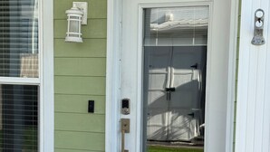 A green house with a white door, a mailbox, and a number '117B' above the door. - Laguna Beach PCB 5/3, STEPS TO THE BEACH-5 STAR RENTAL- CONVENIENT TO EVERYTHING (PANAMA CITY BEACH)