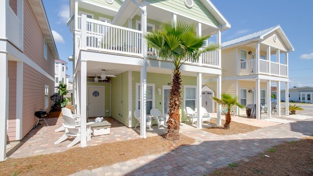 A two-story house with a balcony, outdoor seating, and a small garden. - Laguna Beach PCB 5/3, STEPS TO THE BEACH-5 STAR RENTAL- CONVENIENT TO EVERYTHING (PANAMA CITY BEACH)