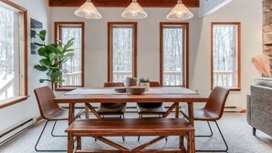 A dining area with a wooden table, chairs, and pendant lights. - Pocono Lake Chalet w/Hot Tub, Pool Table, & Fire Pit. Pet friendly! (Pocono Lake)