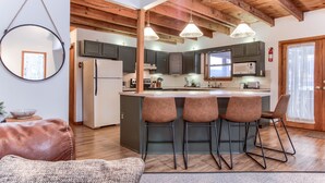 A modern kitchen with wooden beams, a central island with bar stools, and a large mirror on the wall. - Pocono Lake Chalet w/Hot Tub, Pool Table, & Fire Pit. Pet friendly! (Pocono Lake)