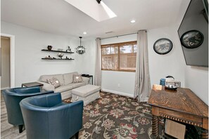 Relax in this stylish living room with a sofa set, ottoman, and armchairs, surrounded by decorative shelves and a large window.