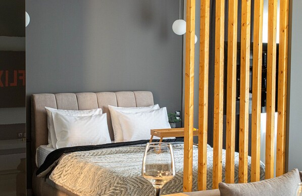 Une chambre à coucher avec un lit, des oreillers, un verre d’eau et une cloison en bois.