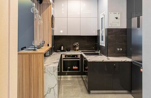Une cuisine moderne dotée d’un plan de travail en marbre, d’appareils électroménagers en acier inoxydable et de meubles de rangement en bois.