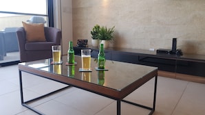 Ein modernes Wohnzimmer mit einem Glastisch, zwei Bierflaschen und Gläsern auf einem Untersetzer.