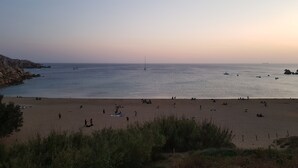 Ein Strand mit entspannten Menschen und Booten im Wasser.