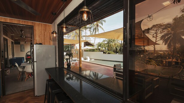 A modern kitchen with a black countertop, wooden ceiling, and pendant lighting. - Beach house El Salvador Brisas Del Mar 99. Just steps from the beach. (Tamanique)