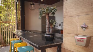 A kitchen with a black countertop, a potted palm tree, and a Coca-Cola branded refrigerator. - Beach house El Salvador Brisas Del Mar 99. Just steps from the beach. (Tamanique)