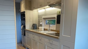 Eine moderne Küche mit grauen Schränken, einer Holz Arbeitsplatte und einem Fenster über der Spüle.