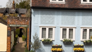 A building with a sign reading "Bridge End Garden" and a staircase leading to a door. There are flower planters on the building's facade. - Miller Cottage - A gorgeous historic cottage in picturesque Saffron Walden (Saffron Walden)