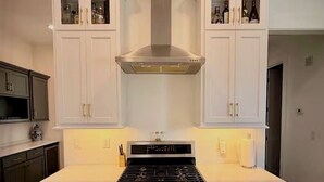 Una cocina con armarios blancos, estufa de acero inoxidable y horno.