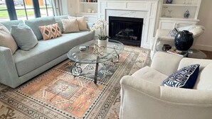 Un salón con sofá, sillón, televisión, chimenea y estanterías.