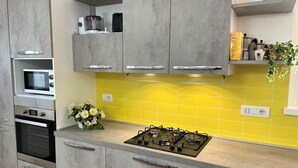 A modern kitchen with grey cabinets, a yellow backsplash, a gas stove, and a built-in oven. - HAPPY DAYS large ground floor apartment with garden and parking. (Intra)