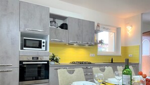 A modern kitchen with grey cabinets, a microwave, oven, and a yellow backsplash. - HAPPY DAYS large ground floor apartment with garden and parking. (Intra)