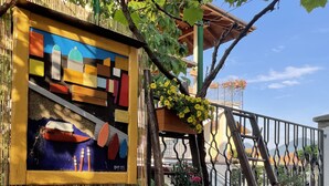 A rustic outdoor seating area with a checkered table, a bamboo fence, and a wooden barrel. - HAPPY DAYS large ground floor apartment with garden and parking. (Intra)