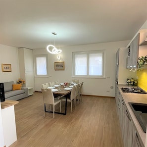 A modern kitchen with a dining area, wooden flooring, and a built-in stove.