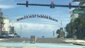Une vue d’une rue avec une enseigne indiquant « DAYTONA BEACH, LA PLAGE LA PLUS CÉLÈBRE DU MONDE » et « Atlantic Ave. »