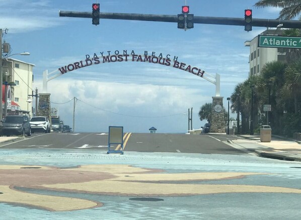 Vista de la calle con un cartel que reza 'DAYTONA BEACH MUNDIALMENTE FAMOSA PLAYA' y 'Atlantic Ave'.