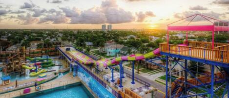 A water park with a long water slide, a pool, and a wooden deck.