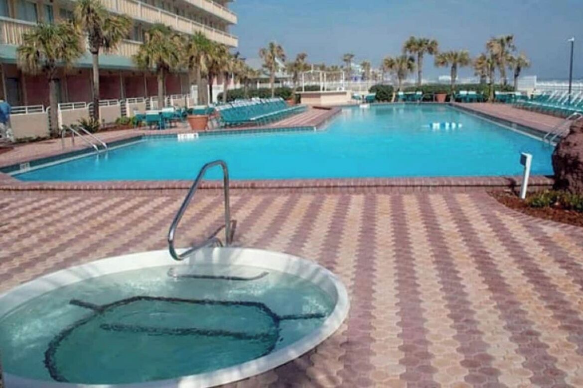 Ein Poolbereich mit Whirlpool, Liegestühlen und Palmen.