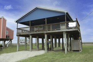 A wooden structure with a balcony, a covered area, and a small attached shed.