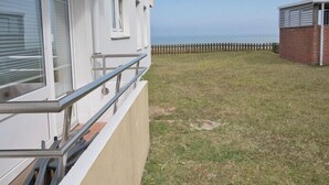 Een gebouw met een balkon, een gazon en een houten omheining.