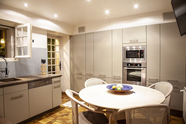 A modern kitchen with white cabinets, a built-in oven, and a dining table with chairs. - IN BALANCE. A COUNTRY HOUSE FULL OF CHARACTER (Carnac-Rouffiac)