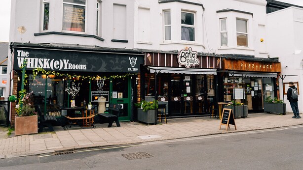 Une vue de rue avec un immeuble abritant les boutiques « The WHISK(e) Rooms » et « Boho Gelato ».