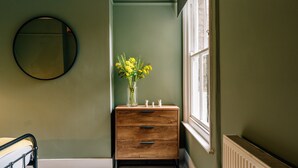 Une pièce avec une commode en bois, un miroir et une fenêtre.