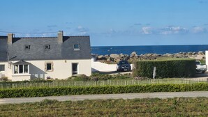 Una zona residencial a la costa amb cases, una valla blanca en esquerdes i vista al mar.