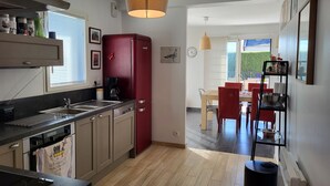 Una cuina compacta amb un frigorífic vermell, una cafetera i una zona de dinar amb cadires i taula vermelles.