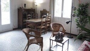 A dining area with a wooden table, chairs, and a lamp. There is a window with curtains and a plant in the corner. - Country house in the heart of nature (mouriès)