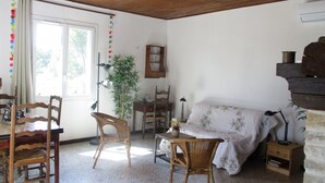 A room with a wooden ceiling, a dining table with chairs, a sofa, a small side table, and a potted plant. - Country house in the heart of nature (mouriès)