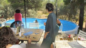 A poolside area with a table, chairs, and a covered seating area. - Country house in the heart of nature (mouriès)